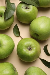 Photo of Fresh green apples and leaves on beige background, flat lay