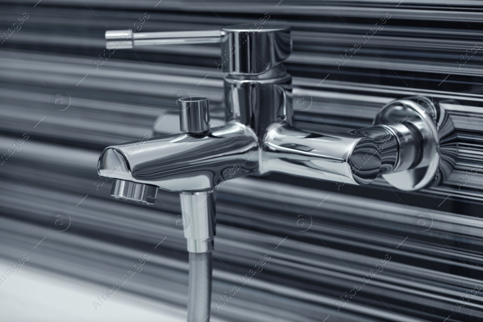 Photo of Shiny bath water tap installed on black and white wall