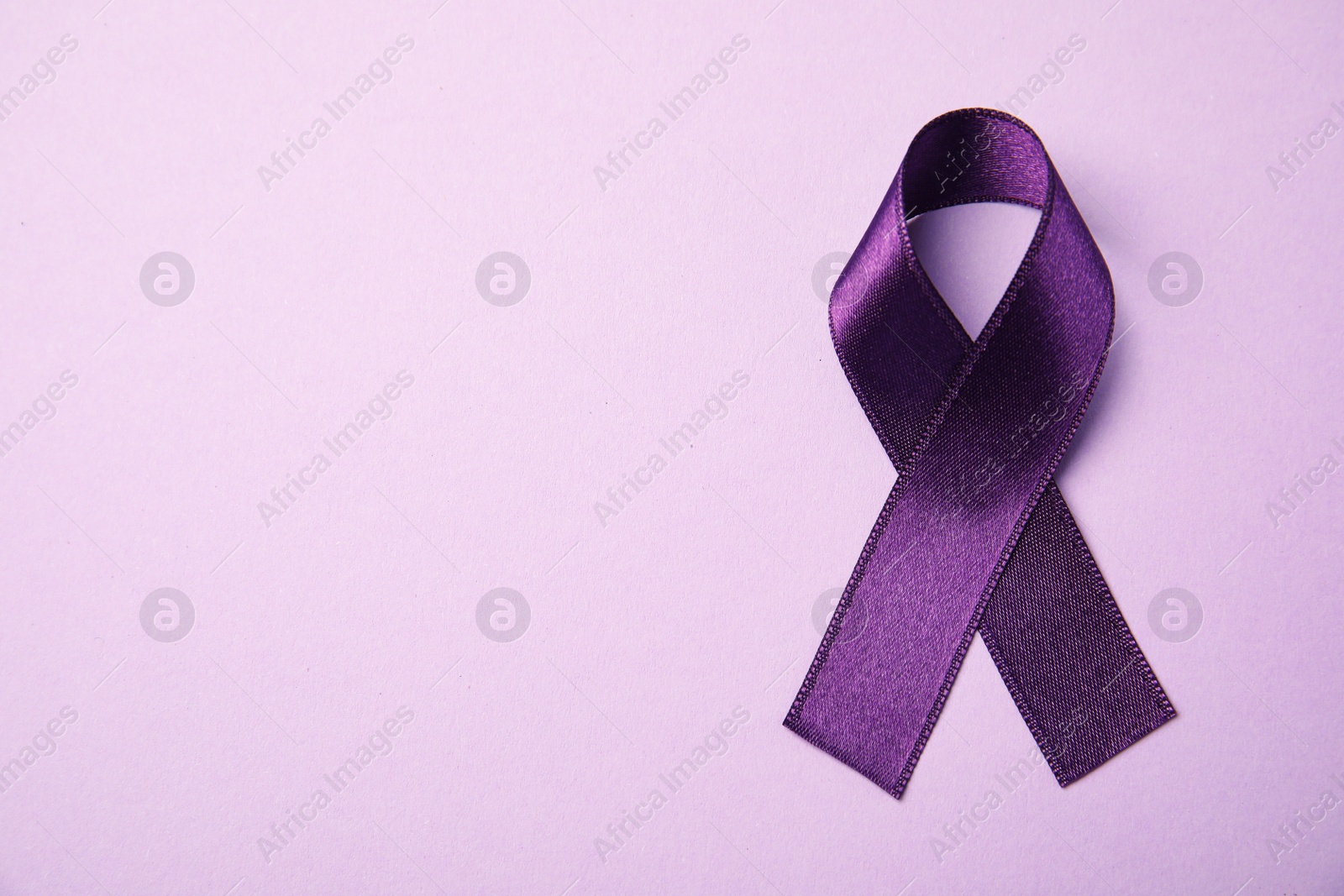 Photo of Purple ribbon on pink background, top view with space for text. Domestic violence awareness