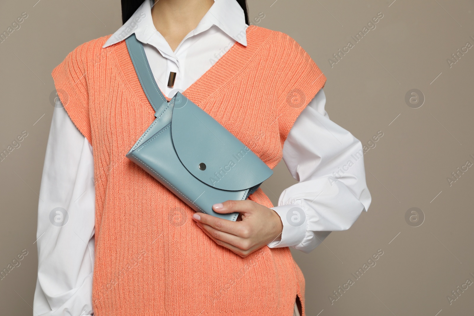 Photo of Young woman with stylish waist bag on grey background, closeup