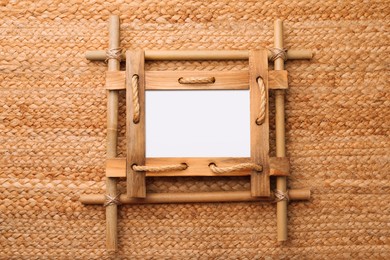 Photo of Empty bamboo frame on wicker straw background, top view. Space for text