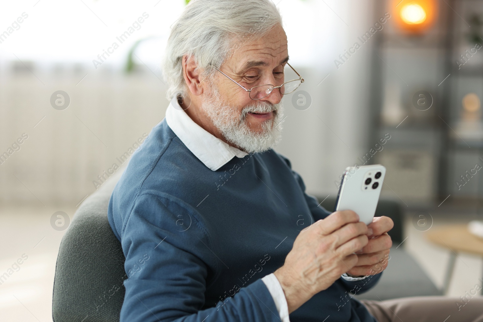 Photo of Portrait of happy grandpa with glasses using smartphone indoors