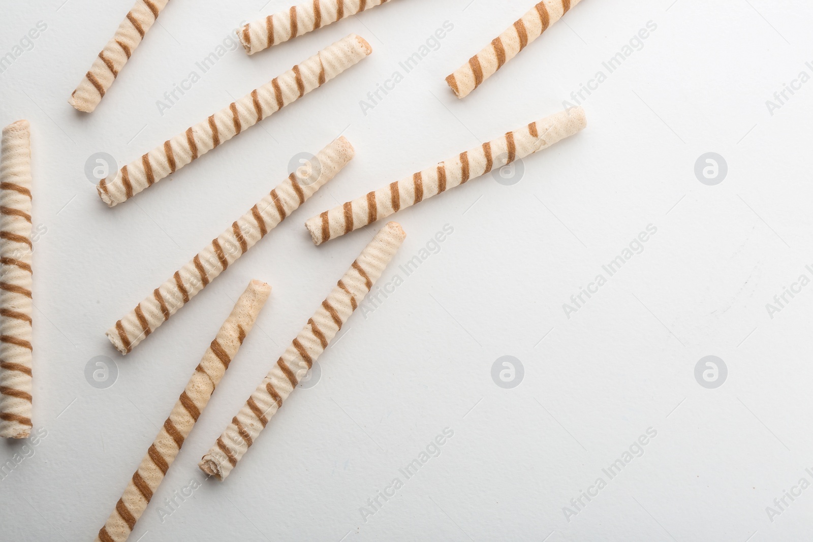 Photo of Delicious wafer rolls on white background, top view with space for text. Sweet food