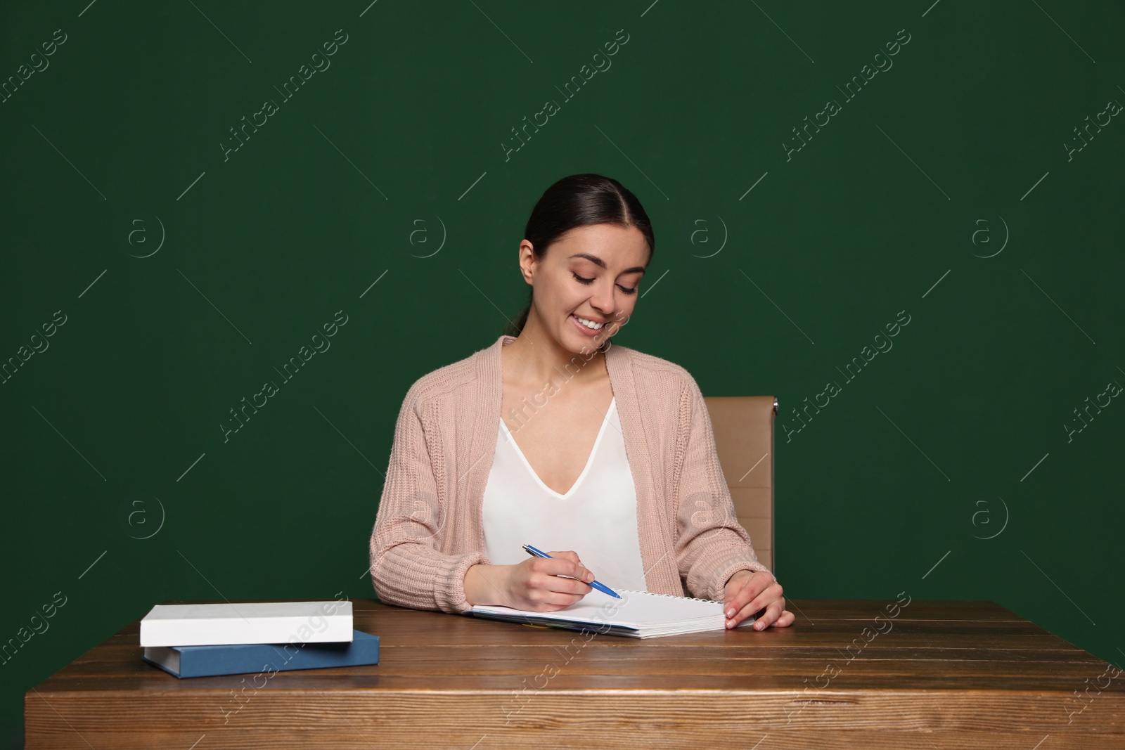 Photo of Portrait of young teacher at table against green background