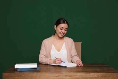 Photo of Portrait of young teacher at table against green background