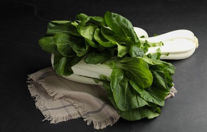 Photo of Fresh green pak choy cabbages on black table