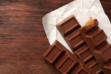 Photo of Tasty chocolate bars on wooden table, top view. Space for text