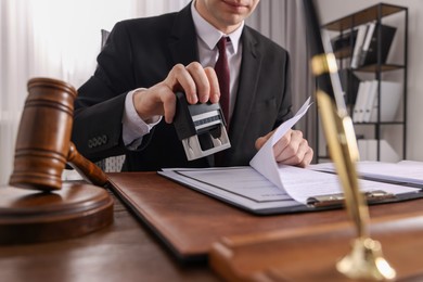 Photo of Notary stamping document at table in office, closeup