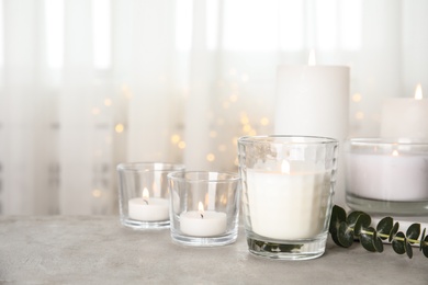 Photo of Burning aromatic candles and eucalyptus branch on table. Space for text