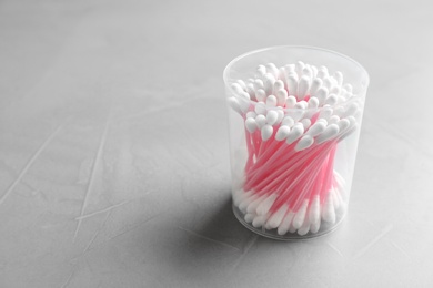 Photo of Plastic container with cotton swabs on grey background. Space for text