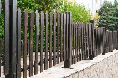 Photo of Low wooden shabby fence near trees outdoors