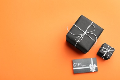 Photo of Gift card and presents on orange background, flat lay. Space for text