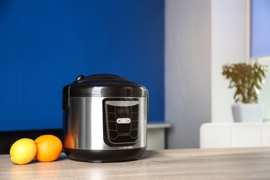 Modern multi cooker and ingredients on table indoors, space for text