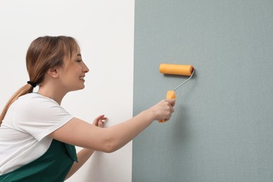 Photo of Worker hanging stylish wall paper sheet indoors