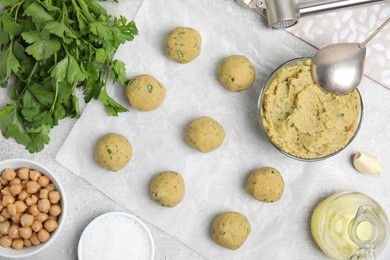 Photo of Raw falafel balls and ingredients on grey table, flat lay