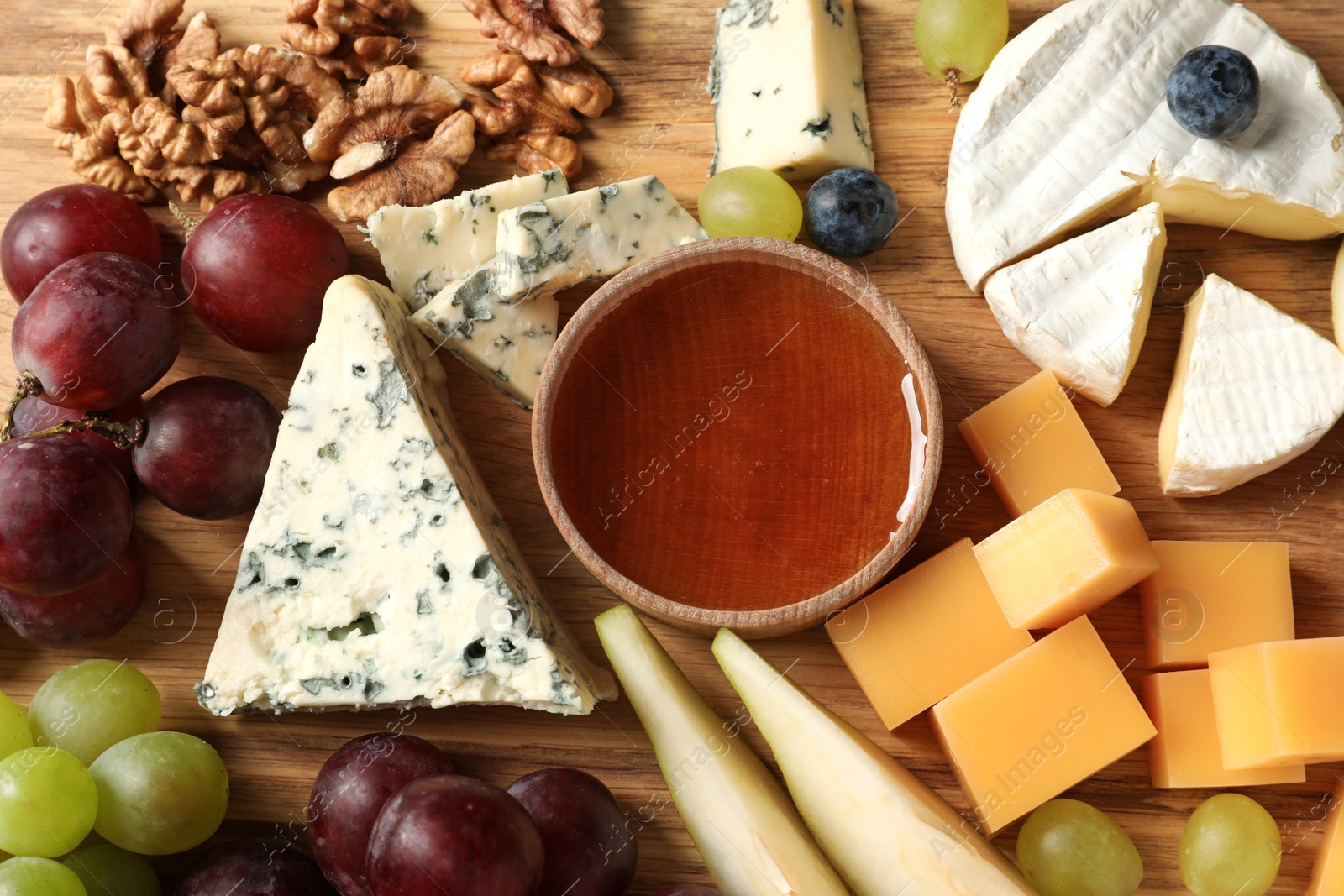 Photo of Different kinds of delicious cheese and snacks on wooden background, top view