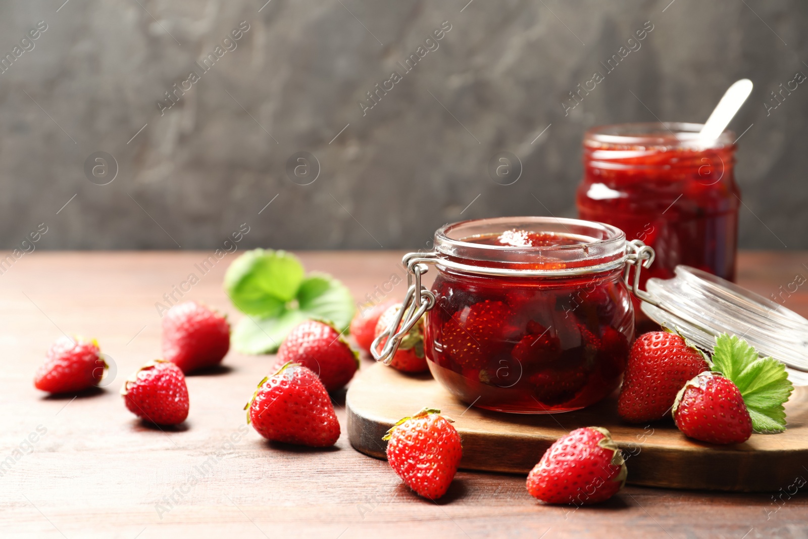 Photo of Delicious pickled strawberry jam and fresh berries on wooden table. Space for text