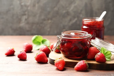 Photo of Delicious pickled strawberry jam and fresh berries on wooden table. Space for text