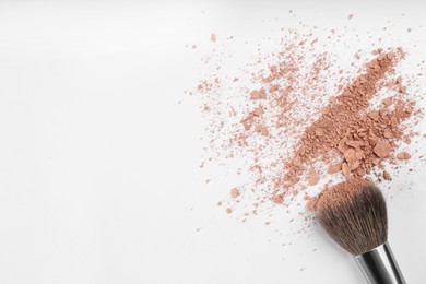 Photo of Makeup brush and scattered face powder on light background, flat lay. Space for text