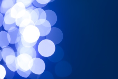 Photo of Blurred view of beautiful lights on blue background, space for text