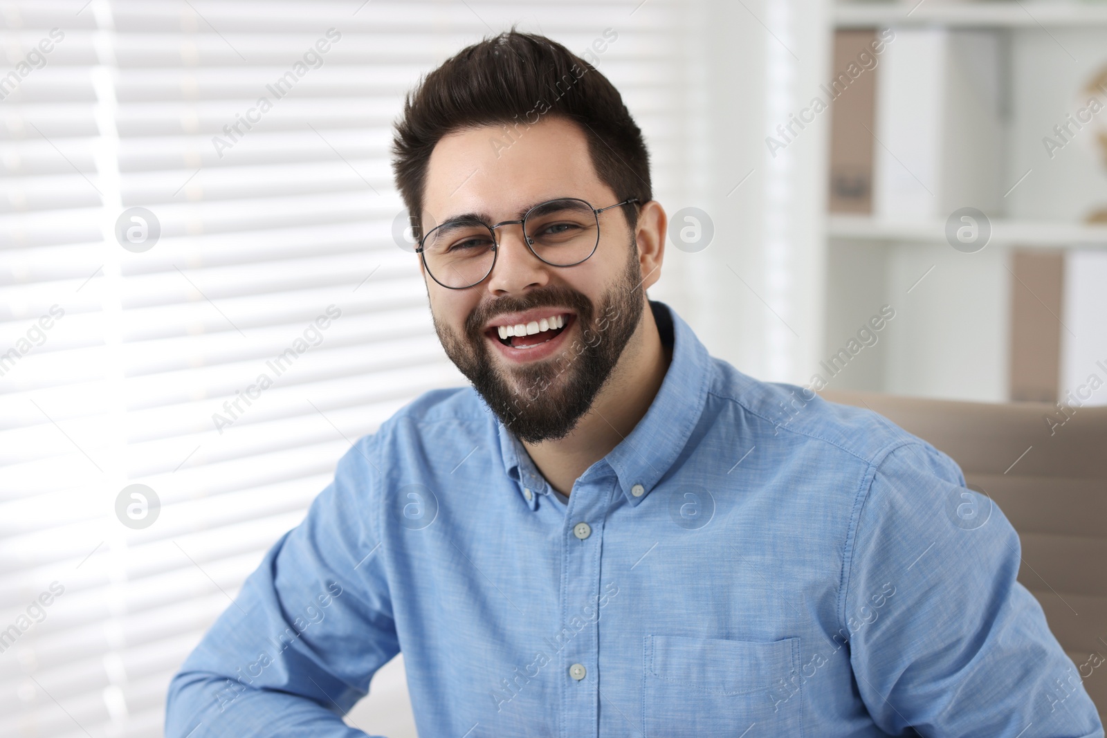 Photo of Portrait of handsome young man laughing in office