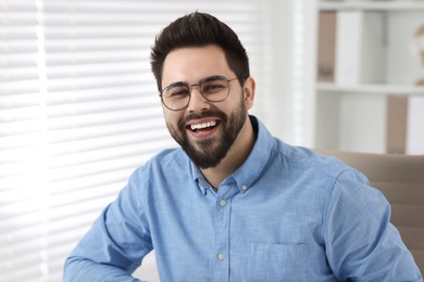 Photo of Portrait of handsome young man laughing in office