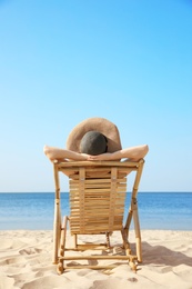 Photo of Young woman relaxing in deck chair on sandy beach