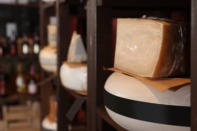 Photo of Different types of delicious cheeses on rack in store