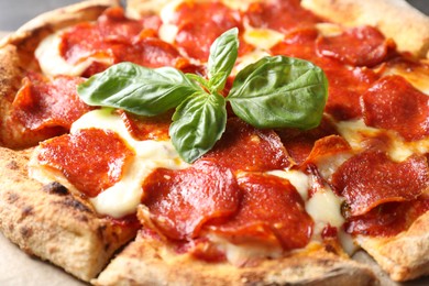 Tasty pepperoni pizza with basil on table, closeup