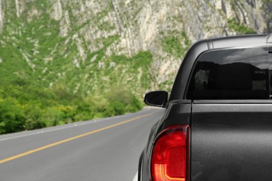 Picturesque view of big mountains and trees near road with black car, space for text