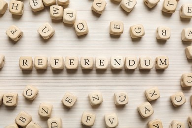 Word Referendum of cubes on white wooden table, flat lay