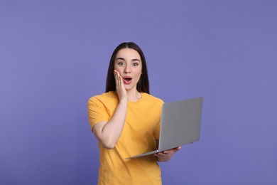 Photo of Surprised young woman with laptop on lilac background