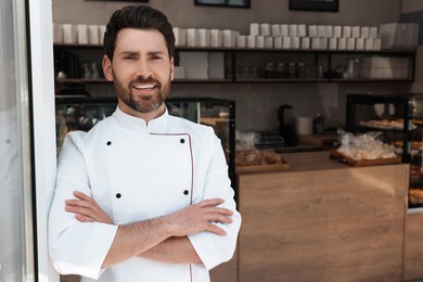 Photo of Portrait of professional baker in bakery shop. Space for text