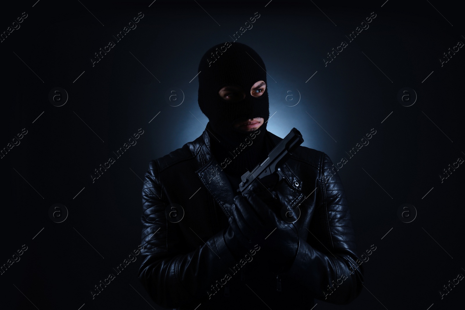 Photo of Man wearing knitted balaclava with gun on black background