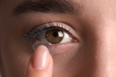 Closeup view of young woman putting contact lens in her eye