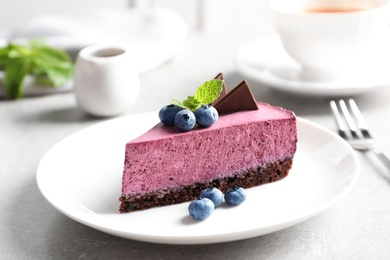 Plate with piece of tasty blueberry cake on gray table