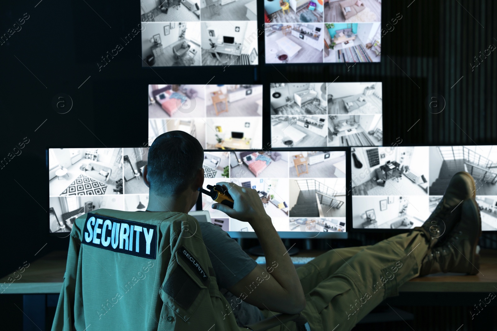 Photo of Security guard with portable transmitter monitoring modern CCTV cameras indoors