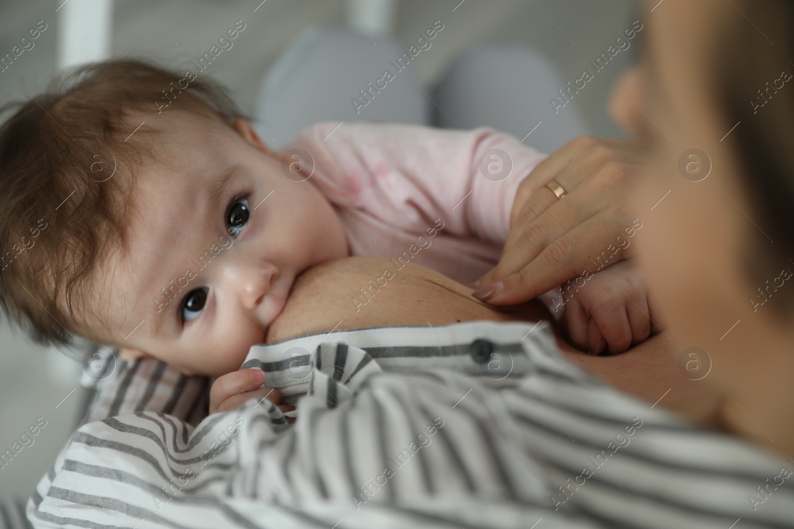 Photo of Young woman breastfeeding her baby at home, closeup