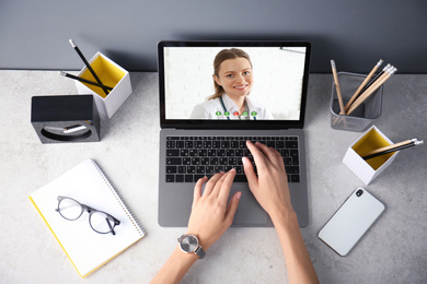 Woman using laptop for online consultation with nutritionist via video chat, top view