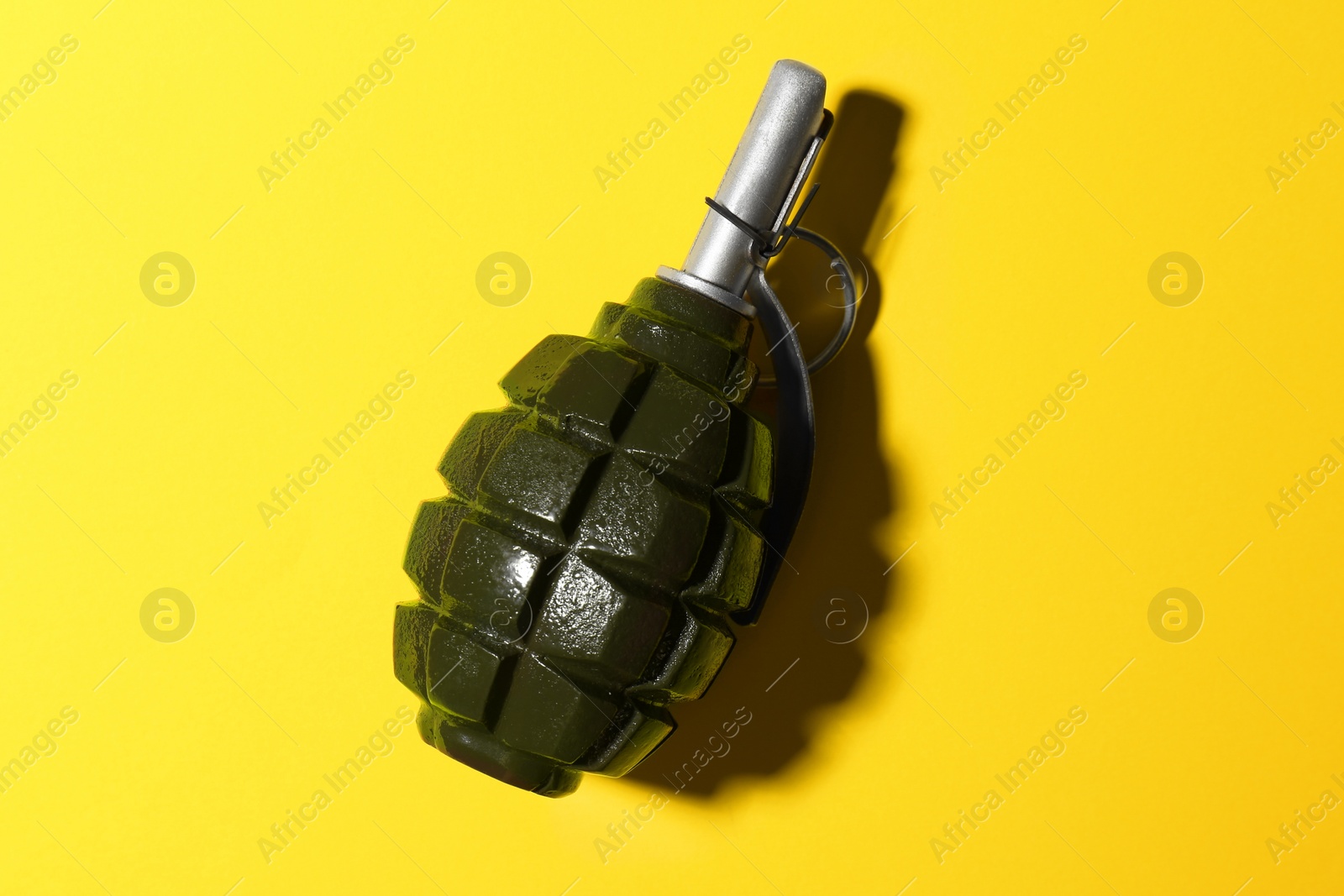 Photo of Hand grenade on yellow background, top view