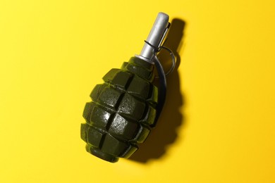 Photo of Hand grenade on yellow background, top view