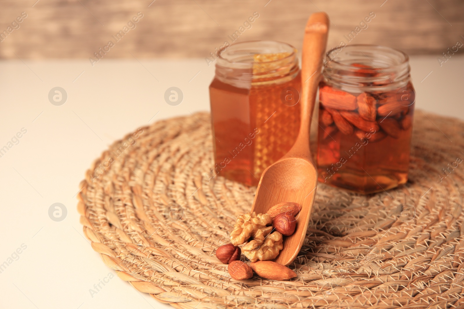 Photo of Jars with almonds and honey, focus on different nuts. Space for text