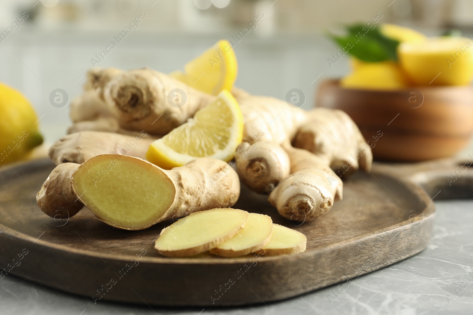 Photo of Fresh lemon and ginger on grey marble table, closeup