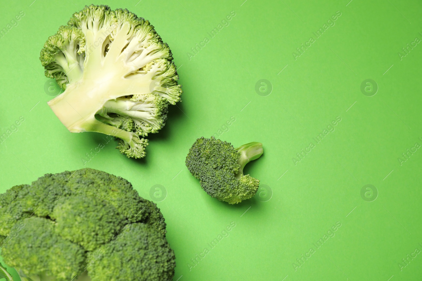 Photo of Fresh broccoli on green background, flat lay. Space for text