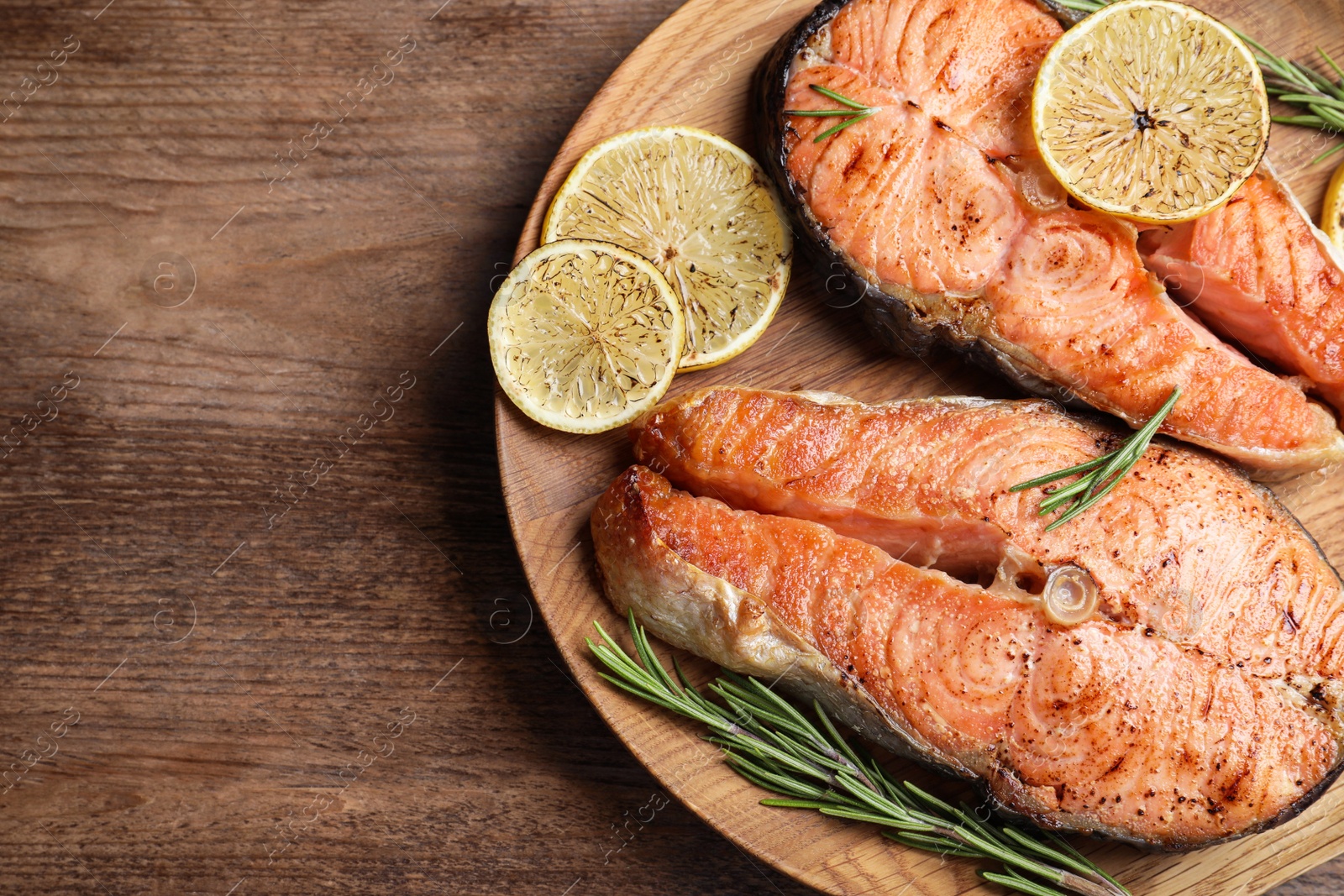 Photo of Tasty cooked red fish on wooden table, top view. Space for text