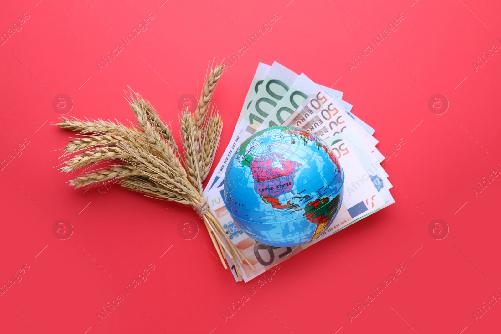 Photo of Import and export concept. Globe, ears of wheat and money on red background, flat lay