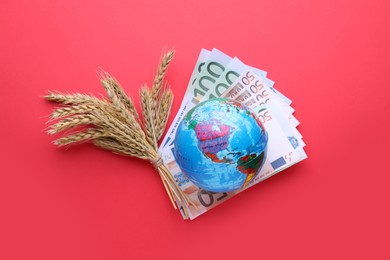 Photo of Import and export concept. Globe, ears of wheat and money on red background, flat lay