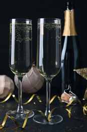 Photo of Happy New Year! Glasses of sparkling wine and festive decor on black background
