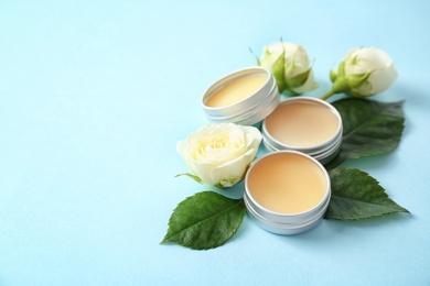 Photo of Hygienic lip balms and flowers on color background