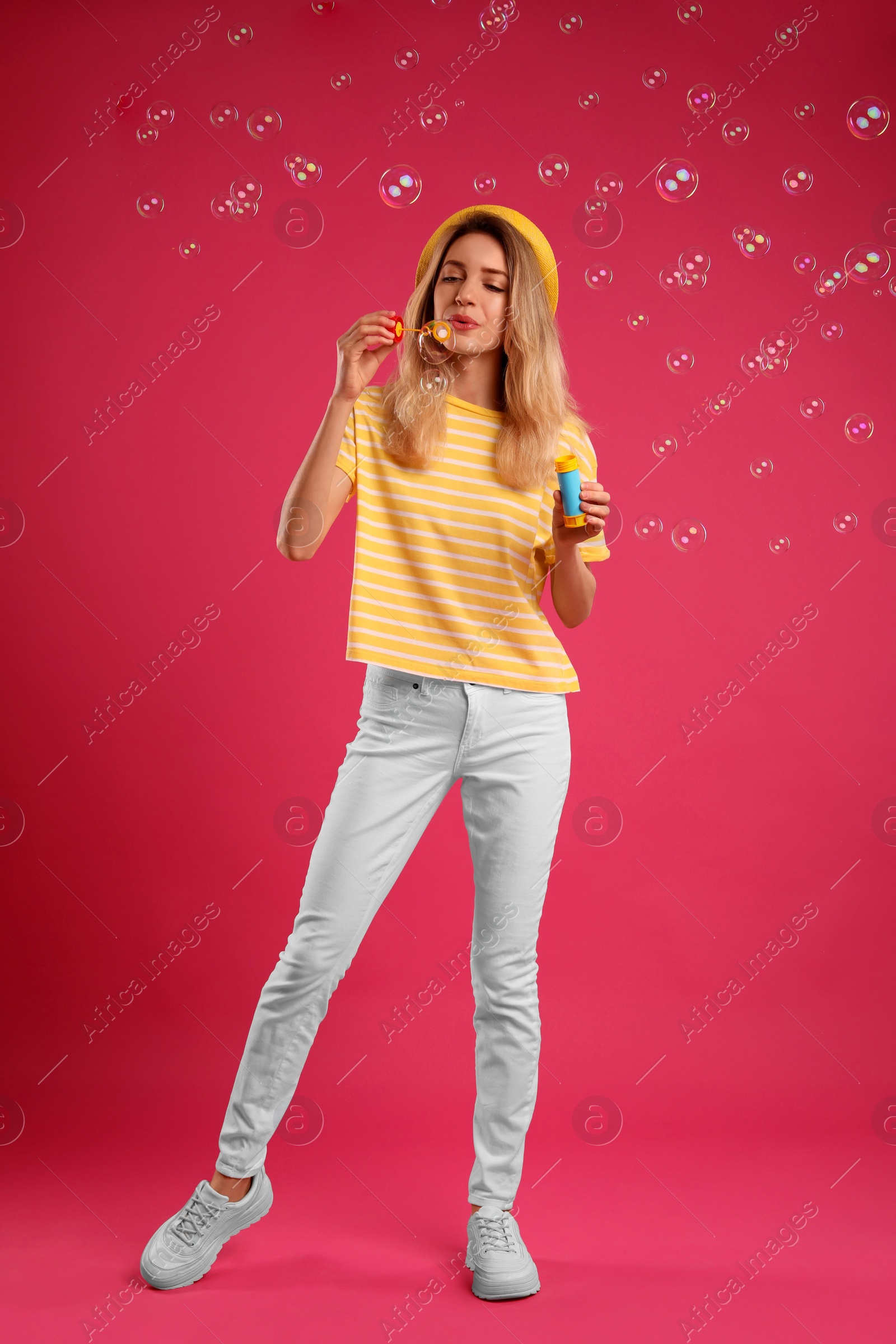 Photo of Young woman blowing soap bubbles on pink background